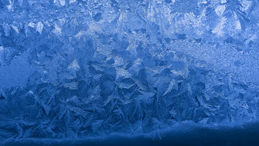 Frost crystal patterns forming intricate geometric shapes on glass in extreme winter cold