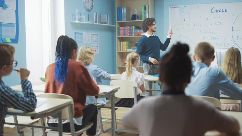 Caring Teacher Explains Lesson to a Classroom Full of Diverse Children. In Elementary School with Group of Smart Multiethnic Kids Learning Science. Slow Motion Moving Camera