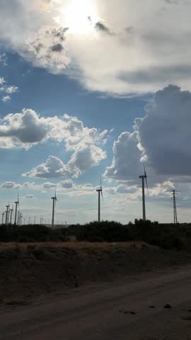 Windswept landscape under a bright sun with spinning turbines in a serene desert setting
