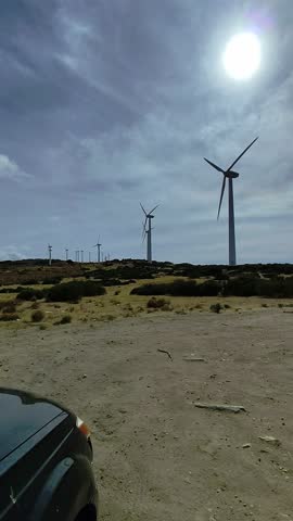 Windswept landscape under a bright sun with spinning turbines in a serene desert setting
