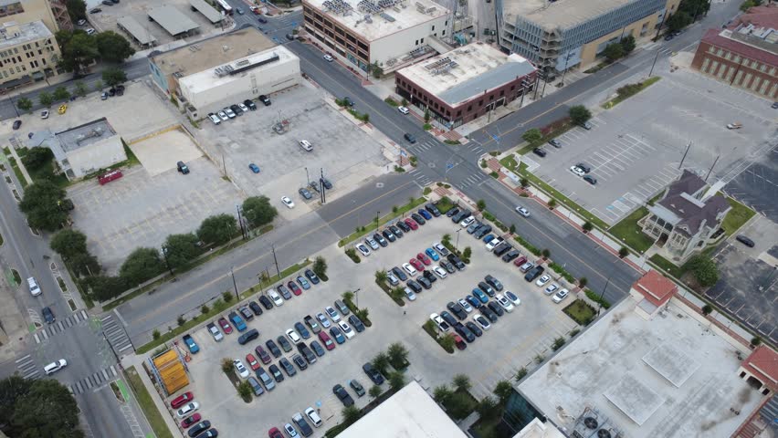 Historic district asphalt lots intersect Commerce Street alongside structured parking zones in historic downtown San Antonio. Urban rooftops overlook grid pavement patterns overcast day in Texas. USA