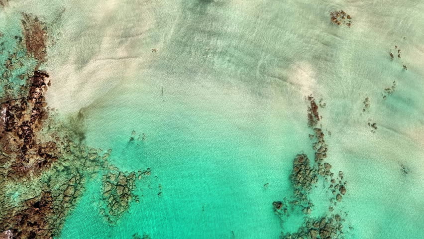 Aerial view of famous Elafonisi beach lagoon with shallow turquoise sea water, pink sand in Crete, Greece on a bright sunny summer day.