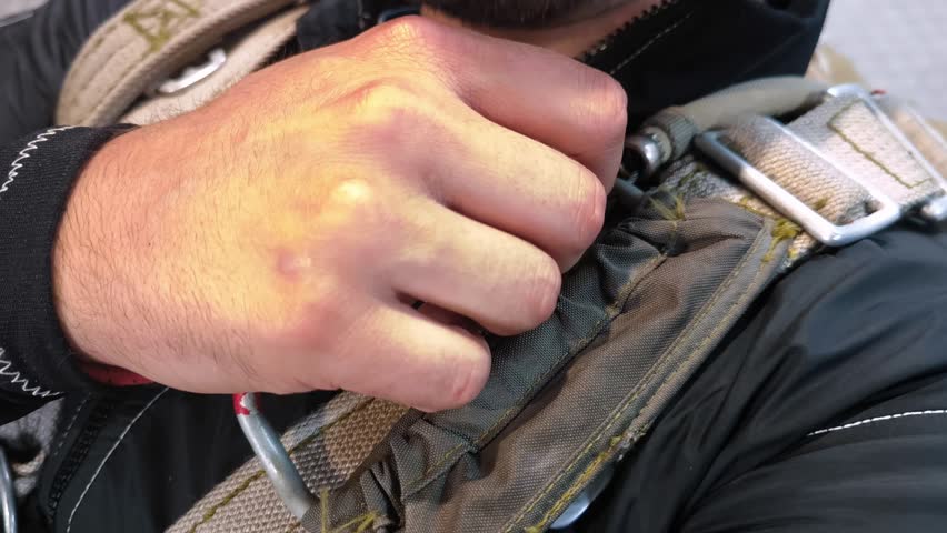The paratrooper tightly squeezes the parachute opening ring before jumping. A close-up of the parachute system element and the preparation for the landing.