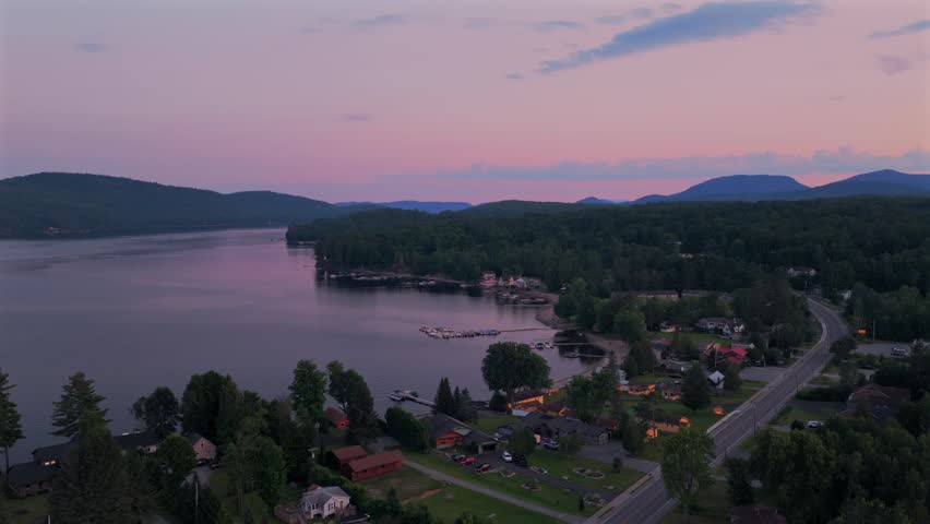 Lake Schroon aerial drone view Town of Schroon Lake Up State New York June July summer sunset clear skies lake homes neighborhood harbor view shoreline beach cove street highway forward motion