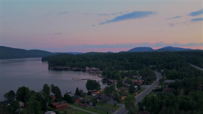 Lake Schroon aerial drone view Town of Schroon Lake Up State New York June July summer sunset clear skies lake homes neighborhood harbor view shoreline beach cove highway upwards motion