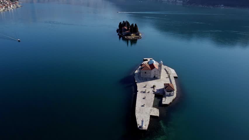 High angle drone shot orbiting Our Lady of the Rocks island church with Saint George Islet in the background, Bay of Kotor, Montenegro.