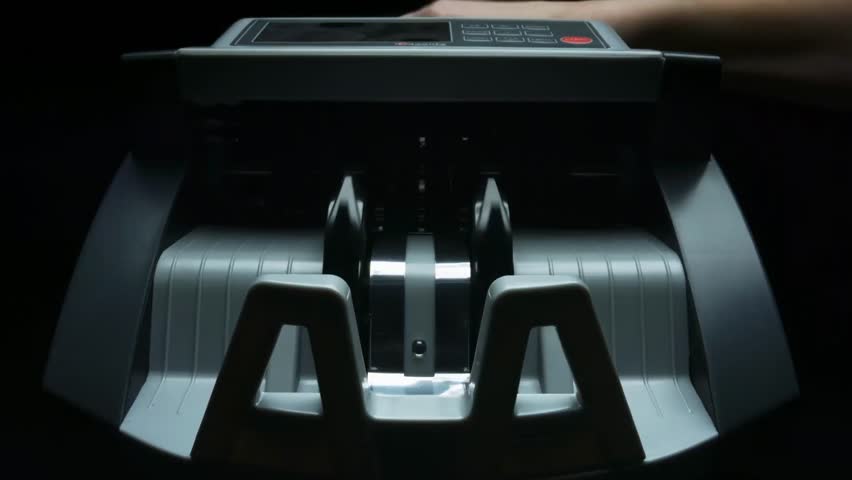 Close-up of an automatic money counting machine processing one hundred US dollar banknotes for banking, finance, cash handling, and currency exchange.