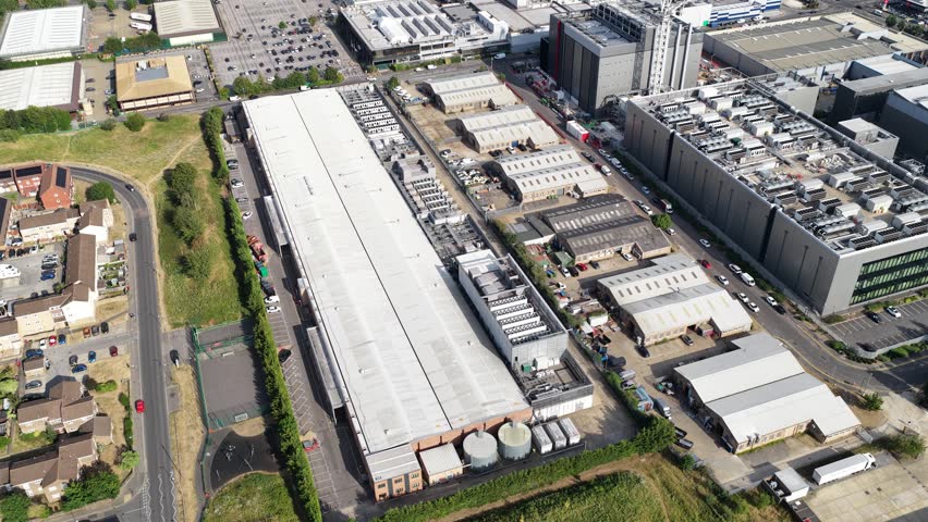 Aerial view of a large datacenter campus with extensive cooling systems on the rooftop, located in a modern industrial park, showcasing the infrastructure for cloud computing and big data