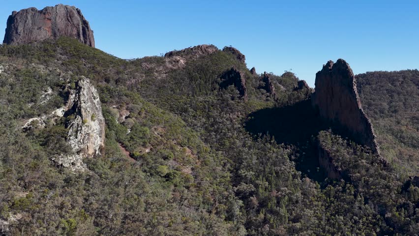 Wide shot of ancient volcanic peaks and eucalyptus forest in Warrumbungle National Park, Australia.