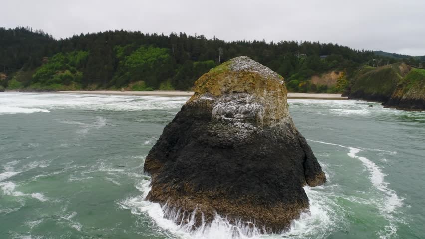 Cinematic high-flying drone orbits low around sea stacks named Bird Rocks and a hidden beach part of the John Yeon State Natural Site, north of Chapman Beach, running along Oregon’s rugged coast.