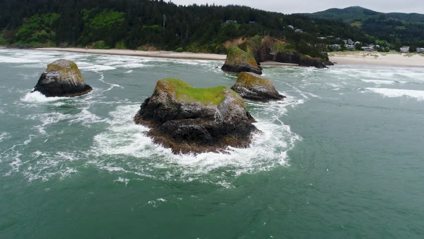 Cinematic high-flying drone reverses far over the ocean, while capturing sea-stacks named "Bird Rocks", and John Yeon State Natural Site, north of Chapman Beach running along Oregon’s rugged coast.
