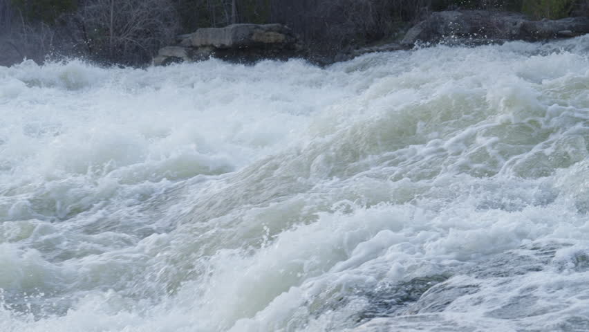 White water rapids surge over submerged limestone rock formations in a forest river. This spring view shows the high volume runoff at Sauble Falls Provincial Park in Ontario.