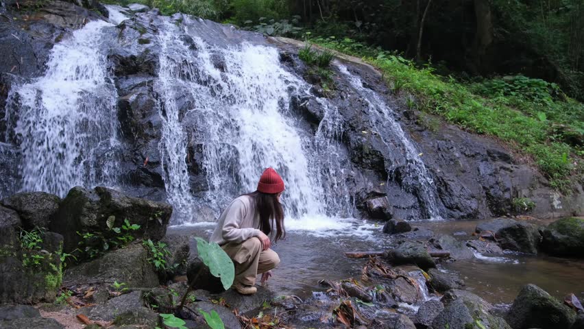 A woman touching and playing with water in the waterfall