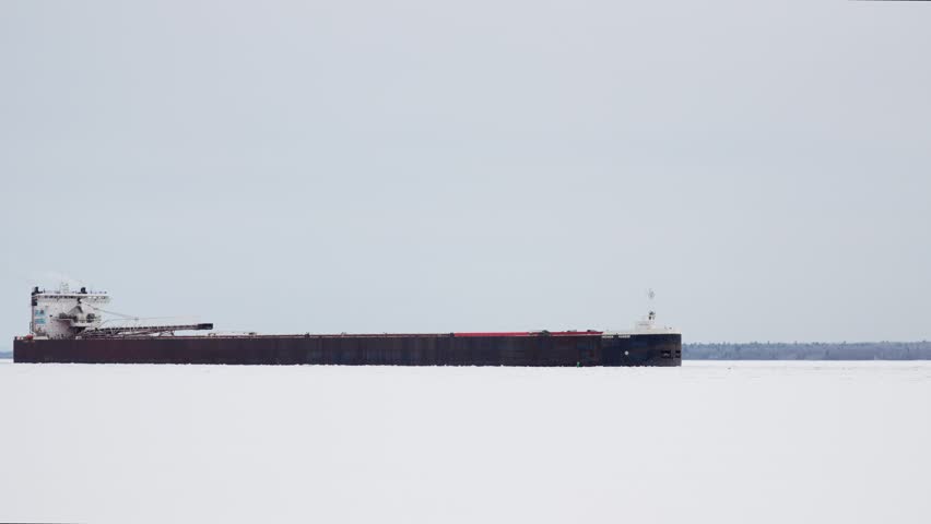 Great Lakes Freighter pushing through ice early in the shipping season. Static shot as they go down the Saint Mary