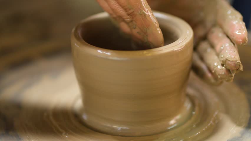 Close-up of skilled hands molding a clay pot on a rotating potter