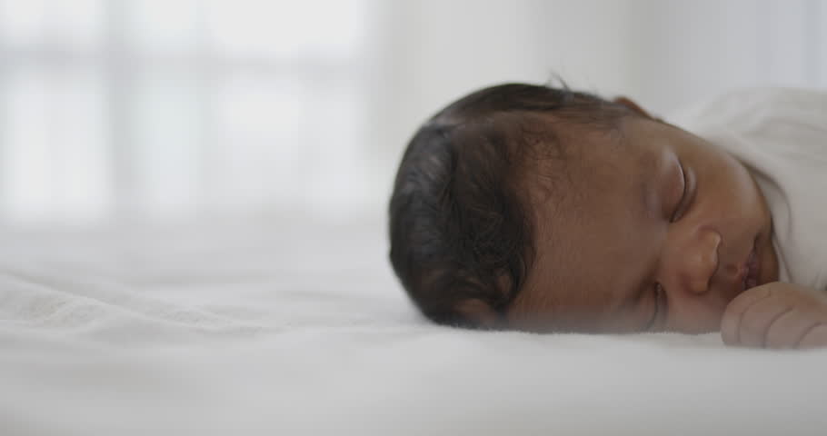 Closeup portrait of african happy baby sleeping sweet dream on bed over white background with copy space. Healthy newborn child take a nap asleep. Family love newborn healthcare medical concept.