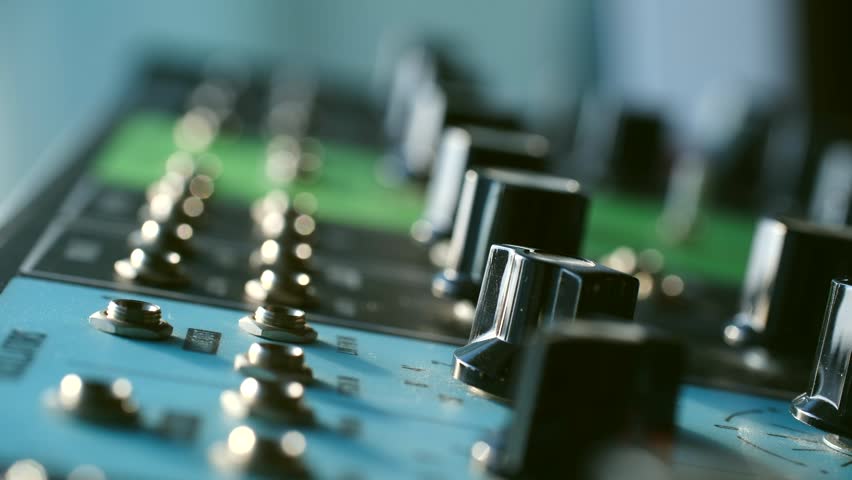 Close up sound engineer hand plugging white jack cable in input of professional audio mixing console, connecting equipment in recording studio or live event setup. 