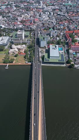 Overhead view tilting up from bridge crossing river revealing dense Bangkok cityscape with distant skyscraper skyline. Rama VIII Bridge, Bangkok, Thailand