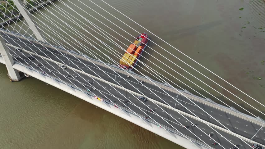 Top-down aerial view of colorful boat traffic beneath the cable-stayed Ba Son Bridge crossing the Saigon River in Ho Chi Minh City, Vietnam.