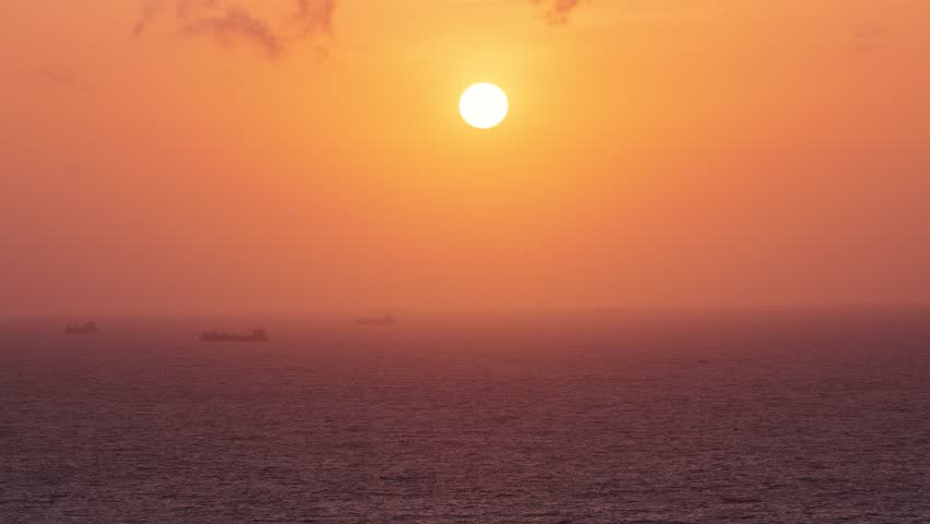 Golden sunset over the Indian Ocean in Sri Lanka with distant ships on the horizon. Peaceful seascape featuring calm waters, warm evening light, and a colorful tropical sky.