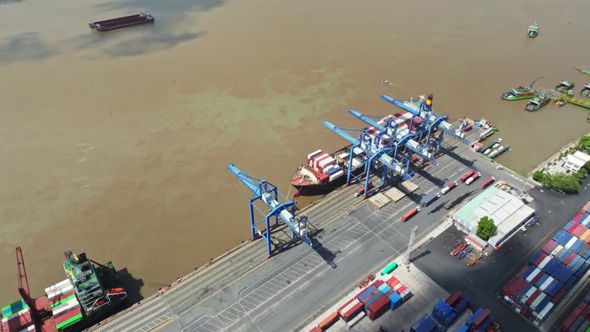 Drone view of Cat Lai container port in Ho Chi Minh City, Vietnam, showing cargo handling operations, gantry equipment, vessels, quay infrastructure, and the Saigon River.