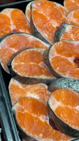 Steaks of chilled Atlantic salmon from frozen raw materials on a substrate for sale in a supermarket. Close-up