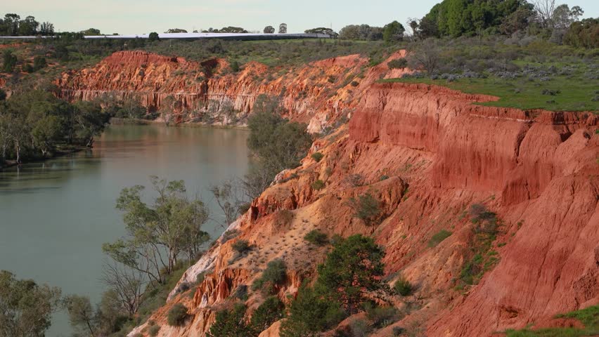 Murray River cliffs showcase Australian nature and its unique landscape, the river system and environmental conservation. Red earth cliffs rise above the calm water