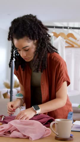 Vertical video: Spreading pink chiffon, woman in rust overshirt pinning seams at studio for sewing. Seamstress, garment, fabric, atelier, daylight, texture, vertical video