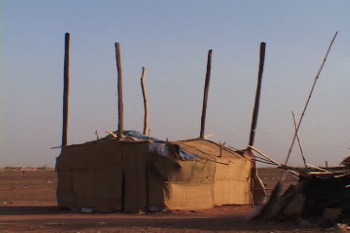 Camp house with tarps on roof and tall poles rising out of the top in refugee camp in Khartoum, Sudan, Africa.