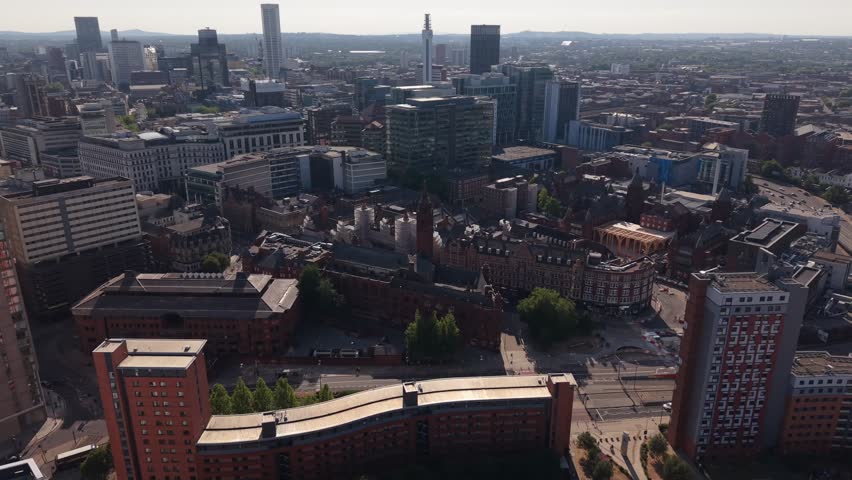 Drone aerial view of Birmingham city centre featuring a mix of historic Victorian architecture, modern office buildings and urban streets under clear summer skies in the West Midlands, England.