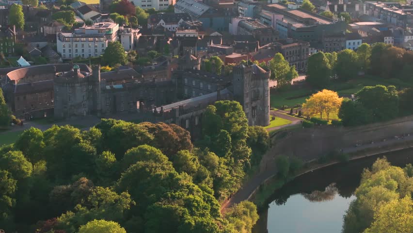 A stunning aerial perspective of Kilkenny Castle and the River Nore at sunset. Captures historic Irish architecture and lush greenery for travel and heritage documentaries.