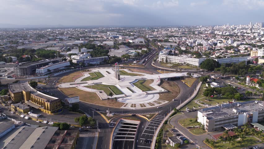 Plaza de la Bandera monument roundabout and cityscape, Santo Domingo in Dominican Republic. Aerial forward