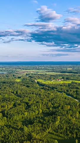 Drone establishing across forests rivers and farmland under blue sky, aerial vertical static timelapse