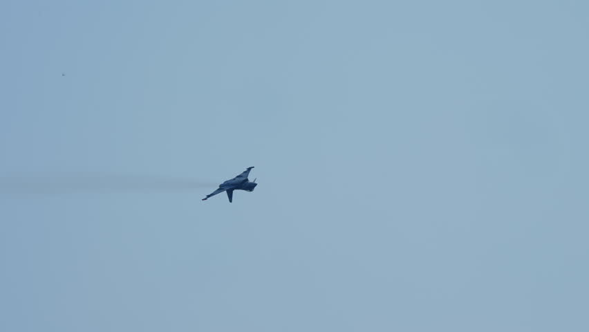 Military fighter jet flying through the sky and performing a sharp bank turn and climb, captured in slow motion as it rises higher in the air