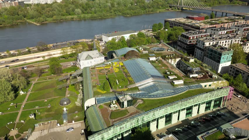 Top aerial shot of the University of Warsaw Library with glass roof panels, green garden areas, modern design and peaceful academic surroundings.