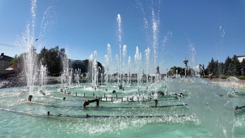 Water fountain sprays water in a park on a sunny day
