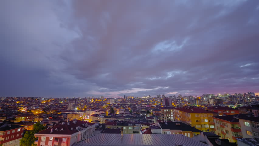 Timelapse: clouds moving over Istanbul residential districts from evening into night in an ultra wide angle view. Windows flickering below and airplane light trails crossing the sky - time lapse