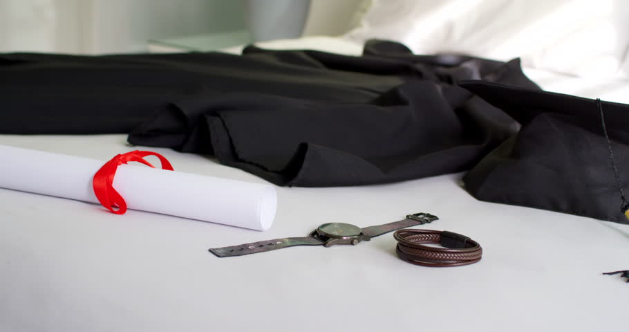 Rolled paper, watch and braided bracelets are resting on table as camera is moving, revealing plant. Flatlay, stilllife, timepiece, bracelet, garment, scroll, daylight