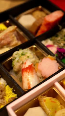 Vertical shot of a traditional Japanese Makunouchi Bento box with colorful dishes, close up