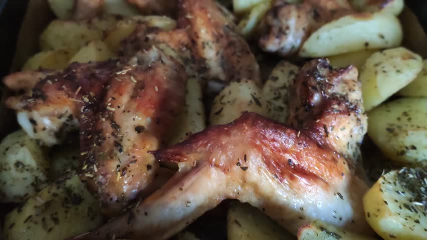Oven-roasted chicken pieces served with golden potato wedges seasoned with herbs and spices. 