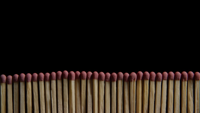 A wall-like row of wooden matchsticks igniting one after another in a chain reaction