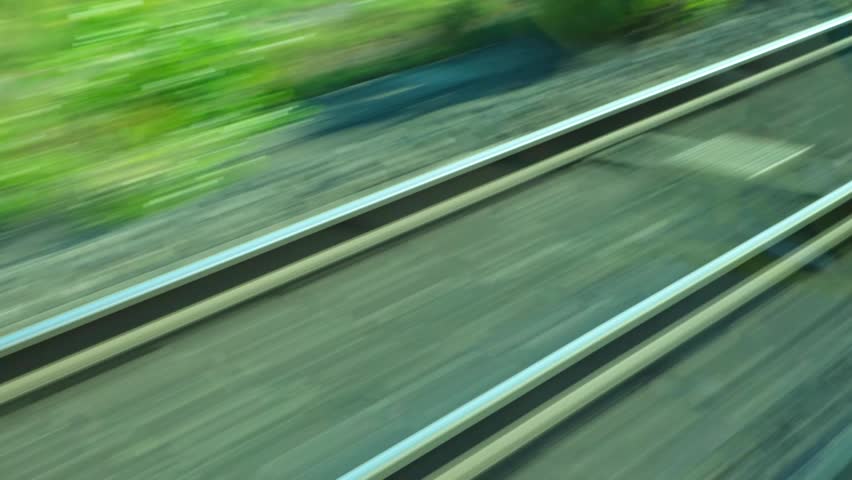 Railway tracks blurs passing by from fast moving train window.