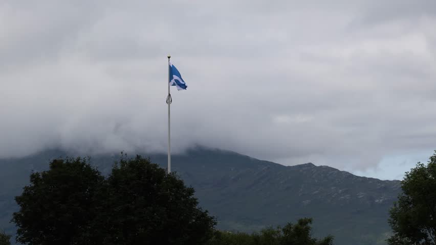 Scottish Saltire Flag Flying with Mountain Landscape in the Highlands of Scotland