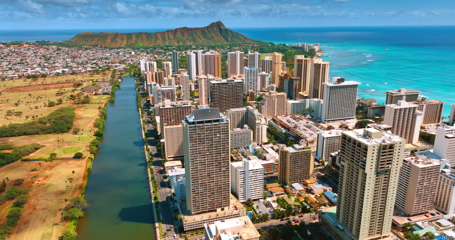 Scenery of resort area Waikiki with beautiful high-rise buildings. Flight above the Ala Wai Canal. Diamond Head Crater at backdrop.