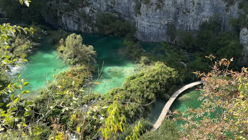 Plitvice Lakes National Park, Croatia. Scenic view of lush green landscape with turquoise water and wooden pathway winding through nature in Croatia