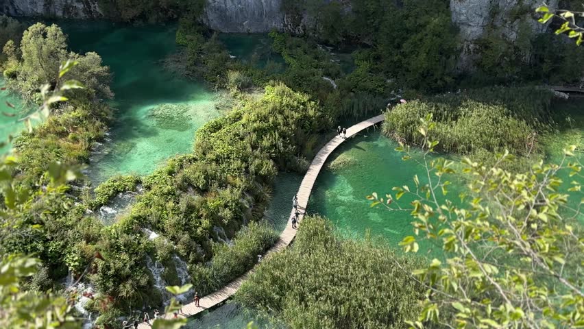 Plitvice Lakes National Park, Croatia. Scenic view of lush green landscape with turquoise water and wooden pathway winding through nature in Croatia