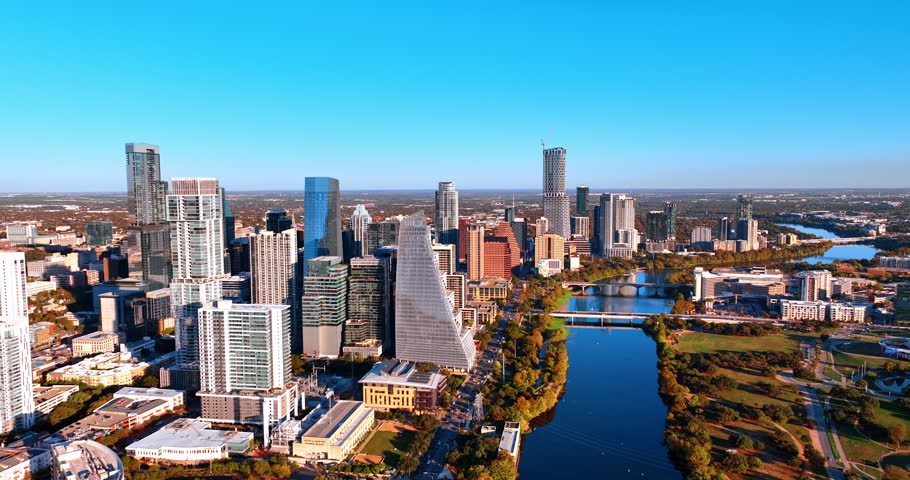 Peaceful wavy Colorado River flowing by the cityscape of Austin, Texas, USA. View on the high-rise downtown locater at the waterfront. Aerial perspective.