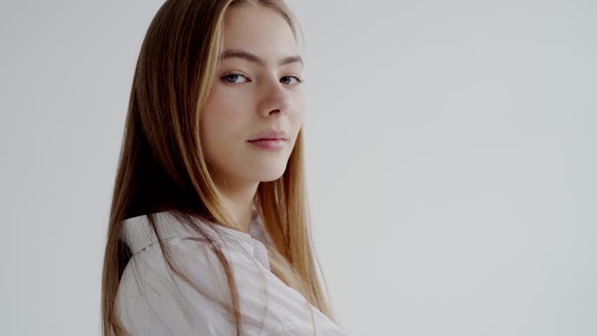 Portrait of a calm young female with long blonde hair, wearing a white shirt and jeans, looking away thoughtfully. Young Woman in Casual Attire Posing with Confident Gaze