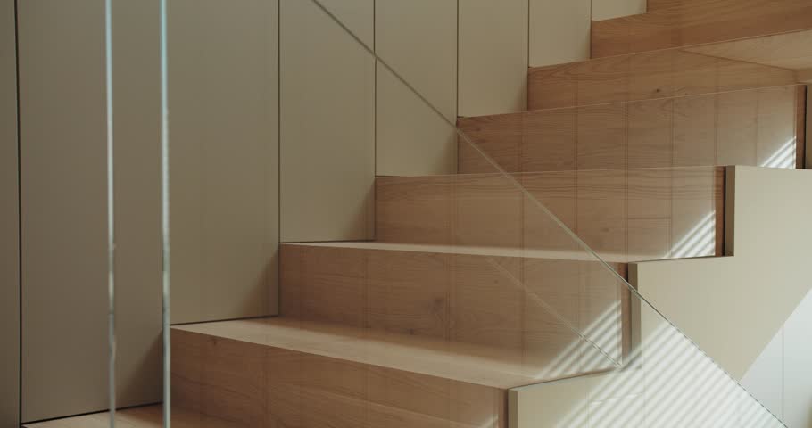 A person climbs a modern wooden staircase, showcasing bare feet and contemporary architecture with natural lighting. Close-Up of Bare Feet Walking Up Wooden Staircase in Modern Home