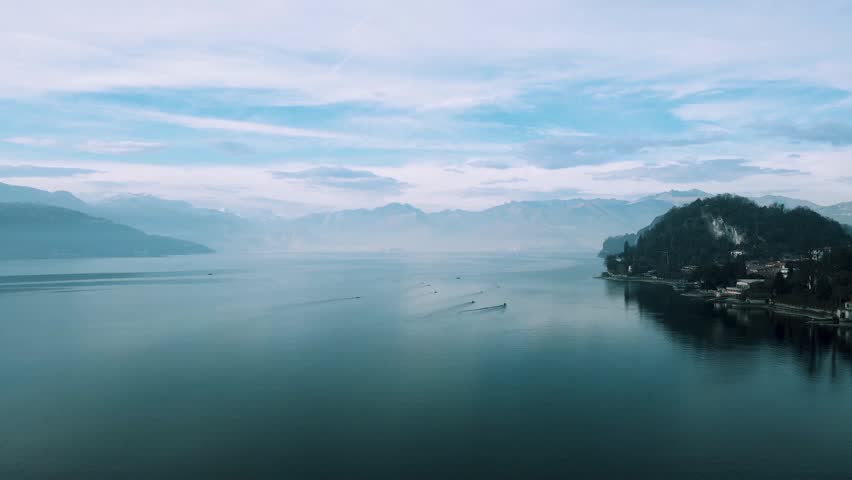 Peaceful aerial view of a calm lake surrounded by mountains and cloudy sky